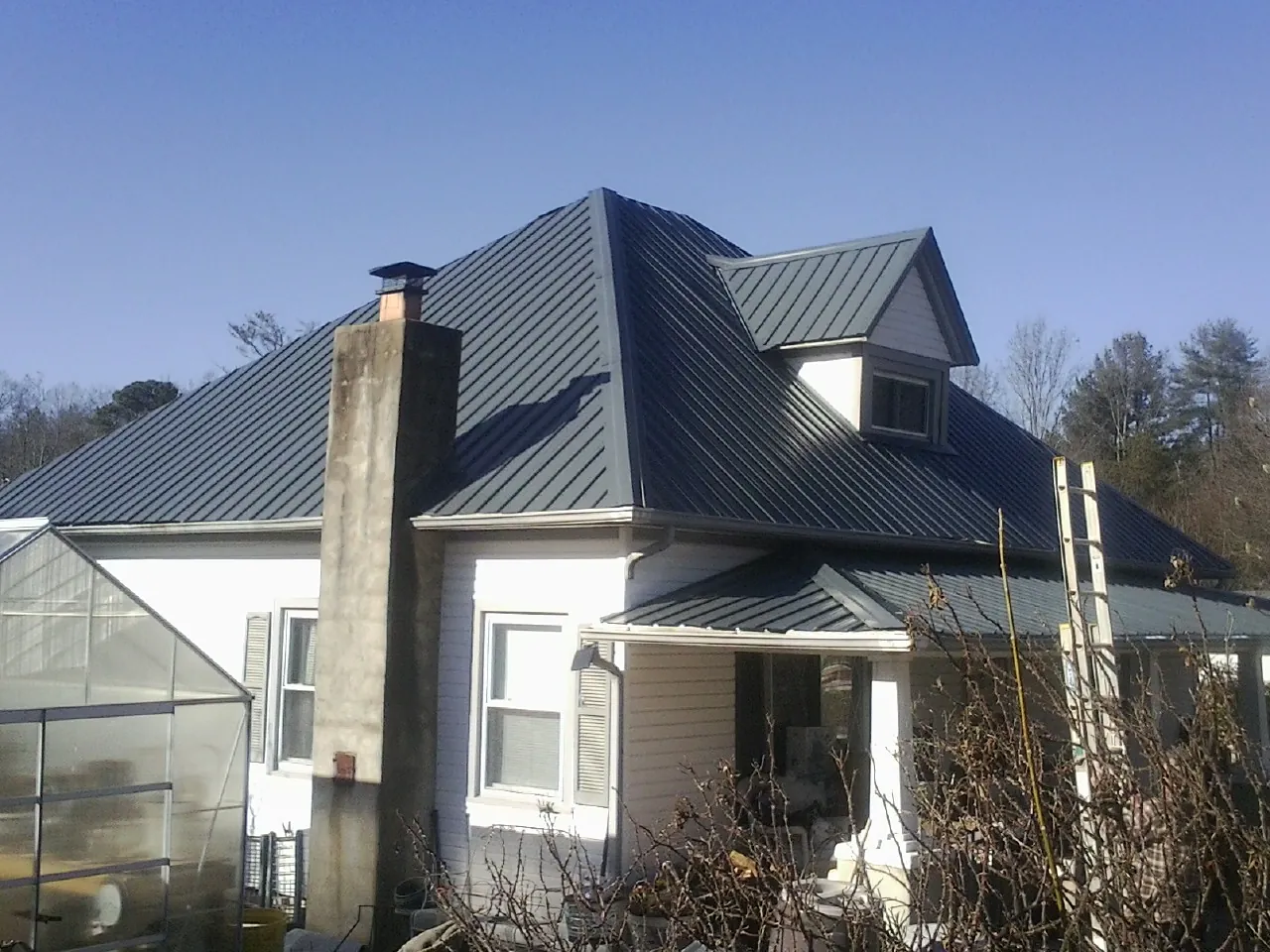 Dark blue standing seam metal roof on a white farmhouse with dormer — Slate & Tile Roof Repair by Roofing Brothers in Pocatello
