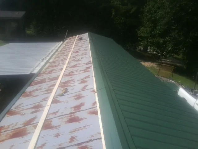 Old rusted panels beside newly installed green metal roofing — Wind Damage Roof Repair by Roofing Brothers in Pocatello