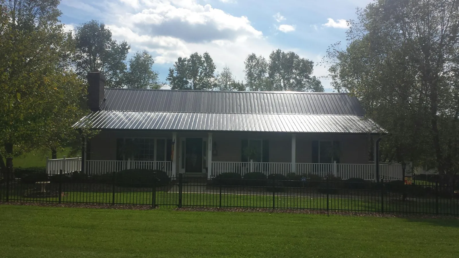Gray metal roof on a brick ranch with a full width front porch — Gutter Guard Installation work by our crew in Pocatello