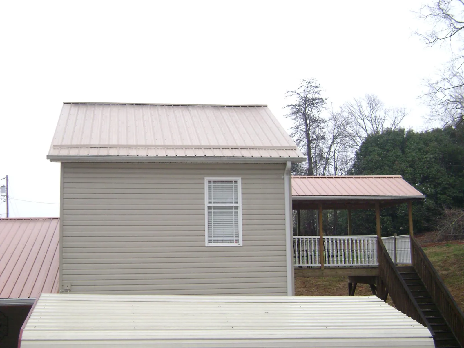 Tan metal roofs on a two story addition and attached porch, from a Roof Replacement job in Pocatello