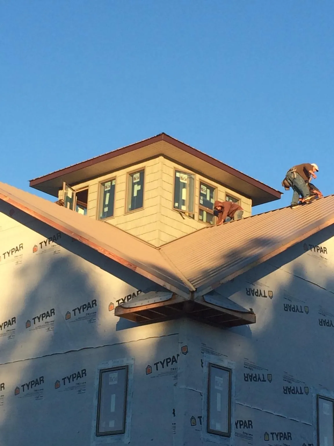 Roofers working around a rooftop cupola on a new metal roof at sunset — Roof Waterproofing in Pocatello by Roofing Brothers